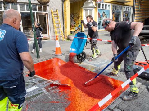 Unnið við að setja rauða málningu á göngugötuna