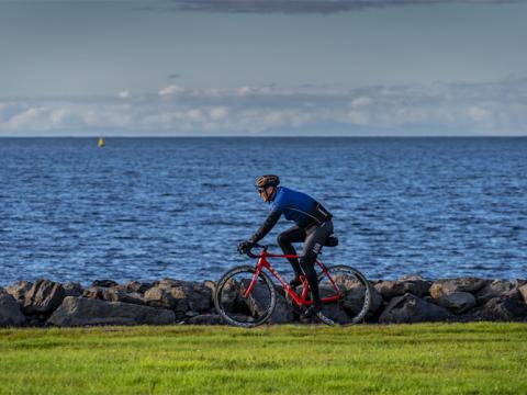 A man biking by the ocean.