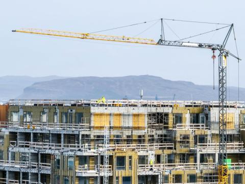 Construction crane. Apartment building under construction. Mountain in the background.