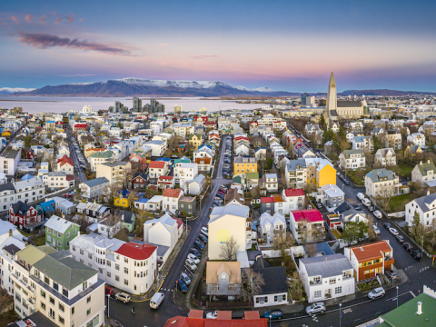 Aerial view of building. Mountain and ocean in the distance.