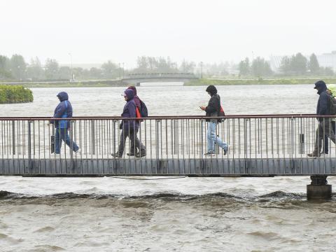 Tourists brave wind and rain on the bridge near City Hall.