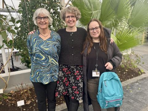 Three women standing in front of plants.
