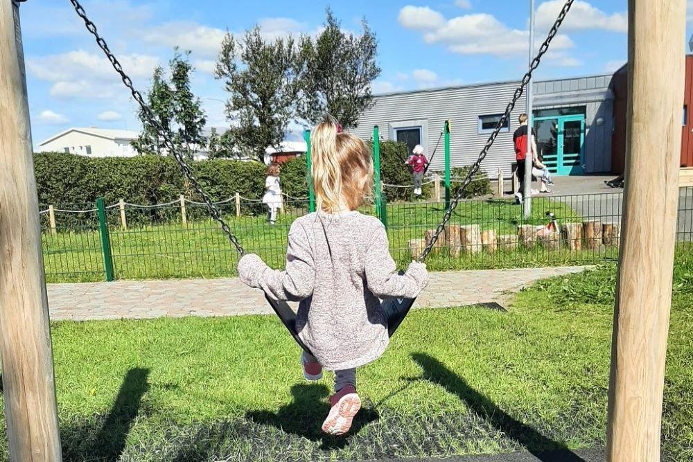 A girl swinging during summer at the playground of Lyngheimar preschool.
