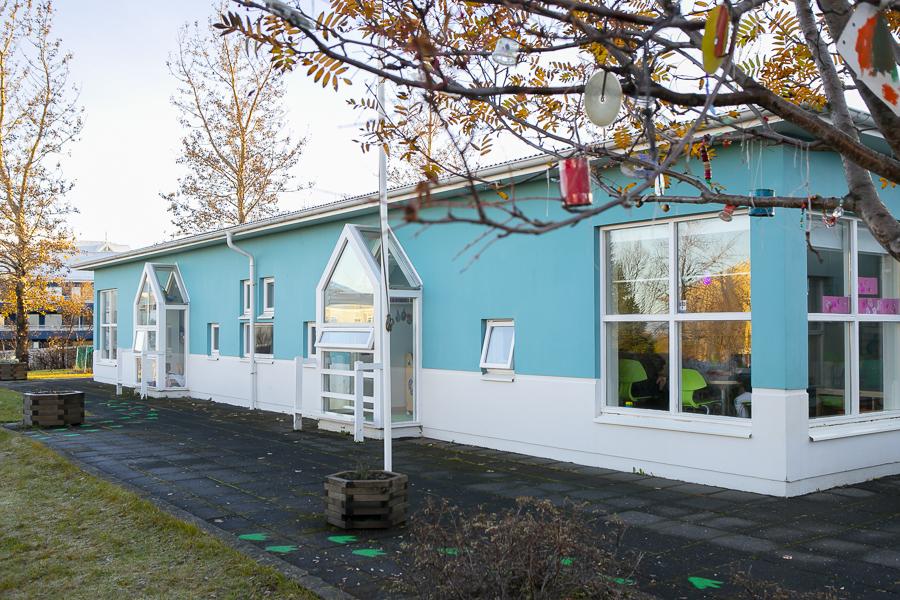 Brekkuborg preschool building viewed from the outdoor area. Leaves and branches in the foreground