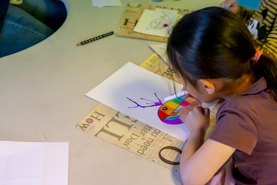 A child lying on the floor drawing a picture at Lyngheimar preschool.