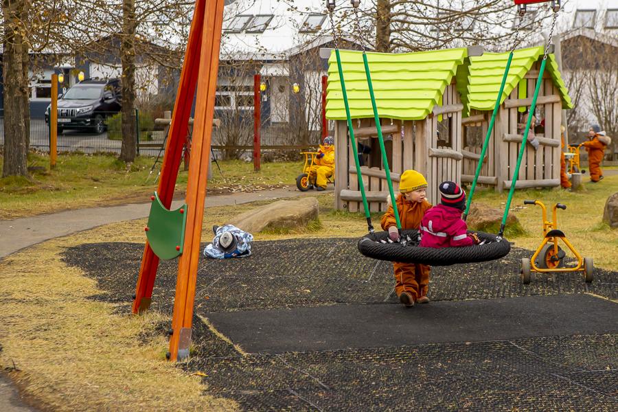 Children on swings with small houses in the background.