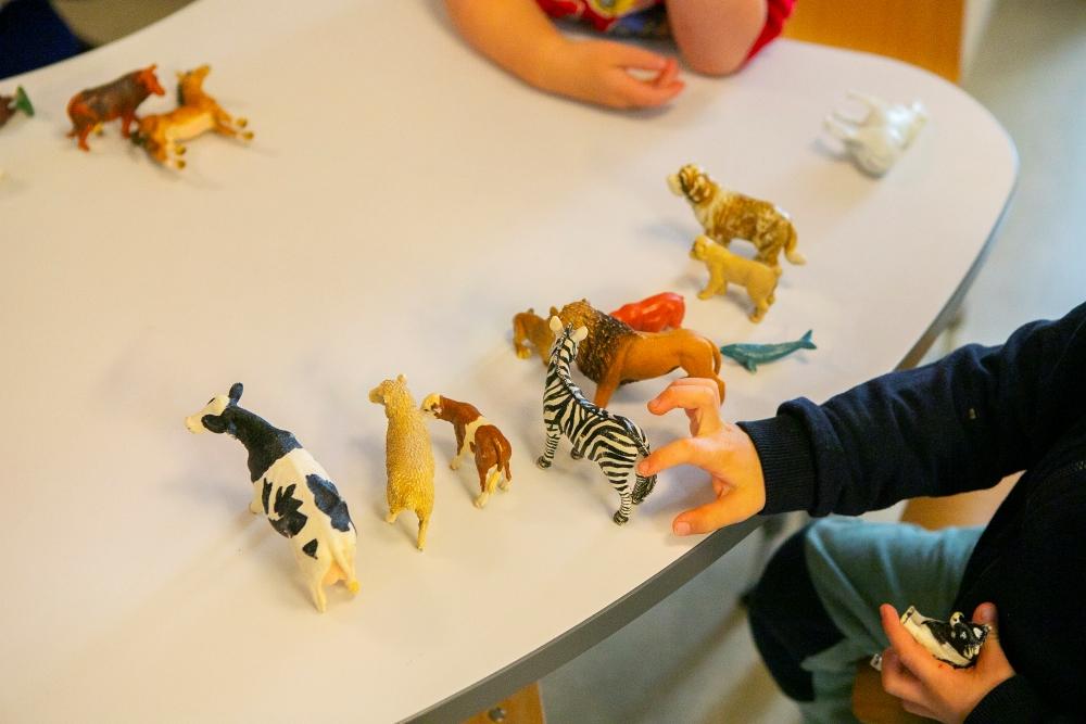 Children playing with plastic animals on a table