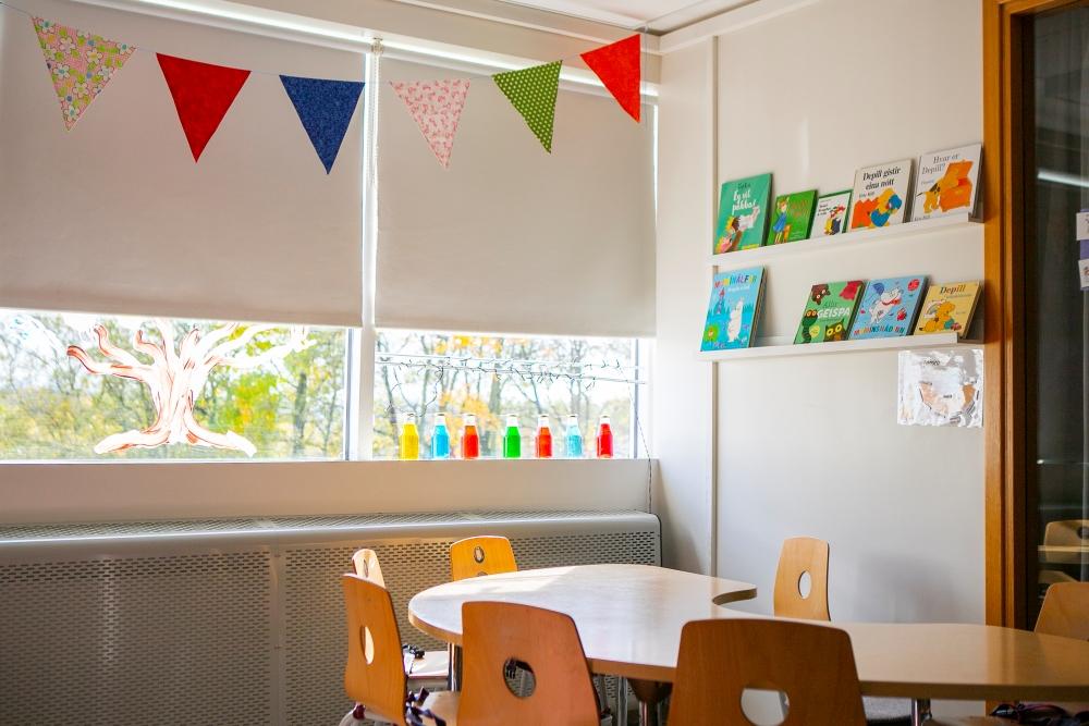 Table and chairs, shelf with books and flag banner on the ceiling.