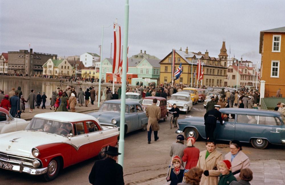 Íslenskum og dönskum fánum flaggað við Tjörnina í Reykjavík 10. apríl 1956 í tilefni af opinberri heimsókn Friðriks IX. Danakonungs og Ingiríðar drottningar. Ljósmyndari Adolf Karlsson.