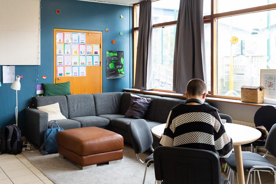 A couch, table, chairs, and a large cushion. A child sits at a table. 