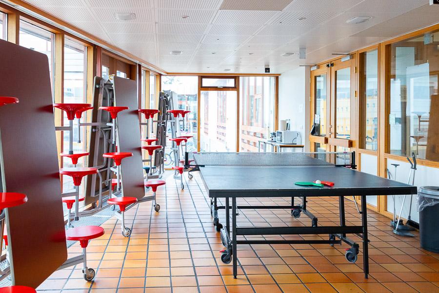 A room with a ping-pong table and folding tables to the side. 