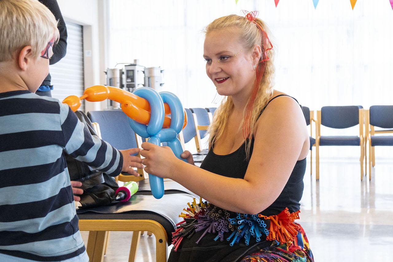 Blöðrulistakona býr til blöðrulistaverk handa barni. 