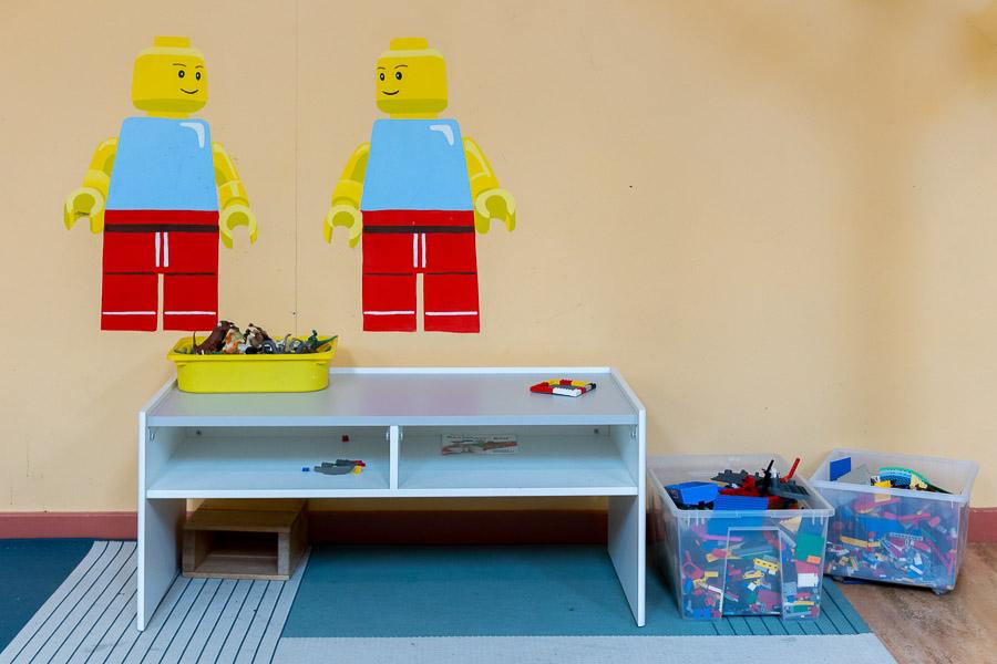 Borð með lego kubbum ásamt myndum af lego fígúrum á vegg