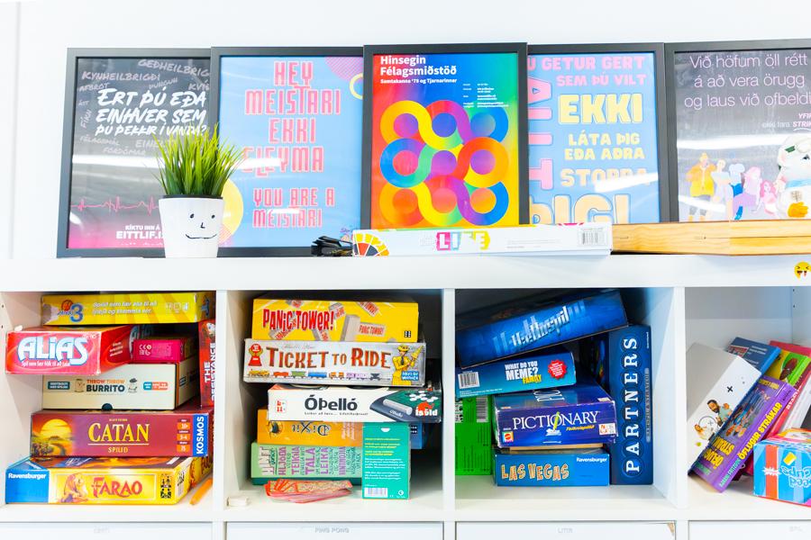 Board games on a shelf and various framed posters above the shelf. 