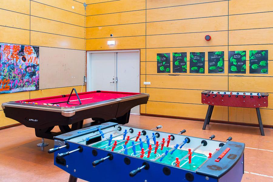 A room with foosball tables and a pool table. 