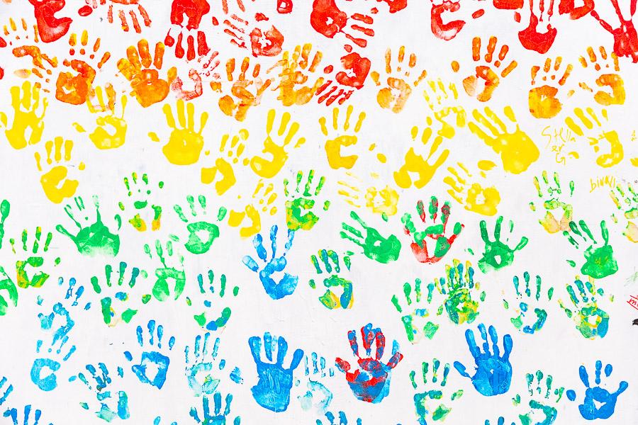 Multicolored handprints on a wall.