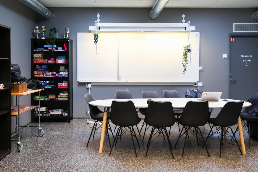 Gray-painted room with a table, chairs and shelf with board games. 