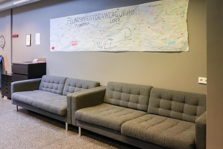 Gray couches against a gray wall. On the wall is a large sheet reading Félagsmiðstöðvadagurinn (Youth Center Day).