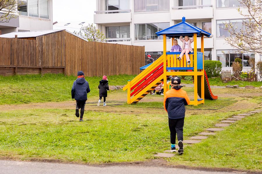 Rennibraut með turni á grasflöt. Börn að leik. 