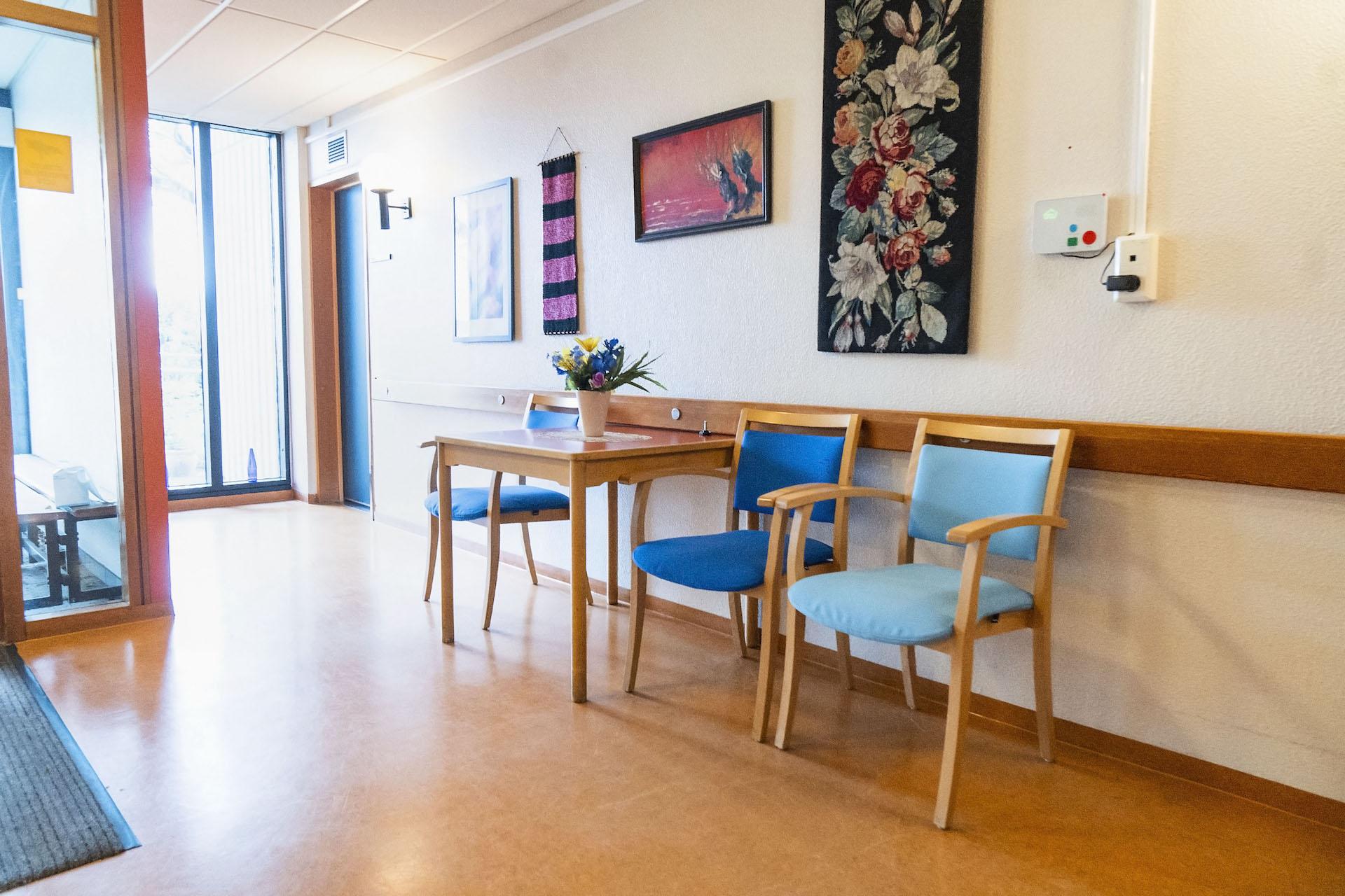 Gangur á Norðurbrún, stólar upp við vegg og borð á milli. 