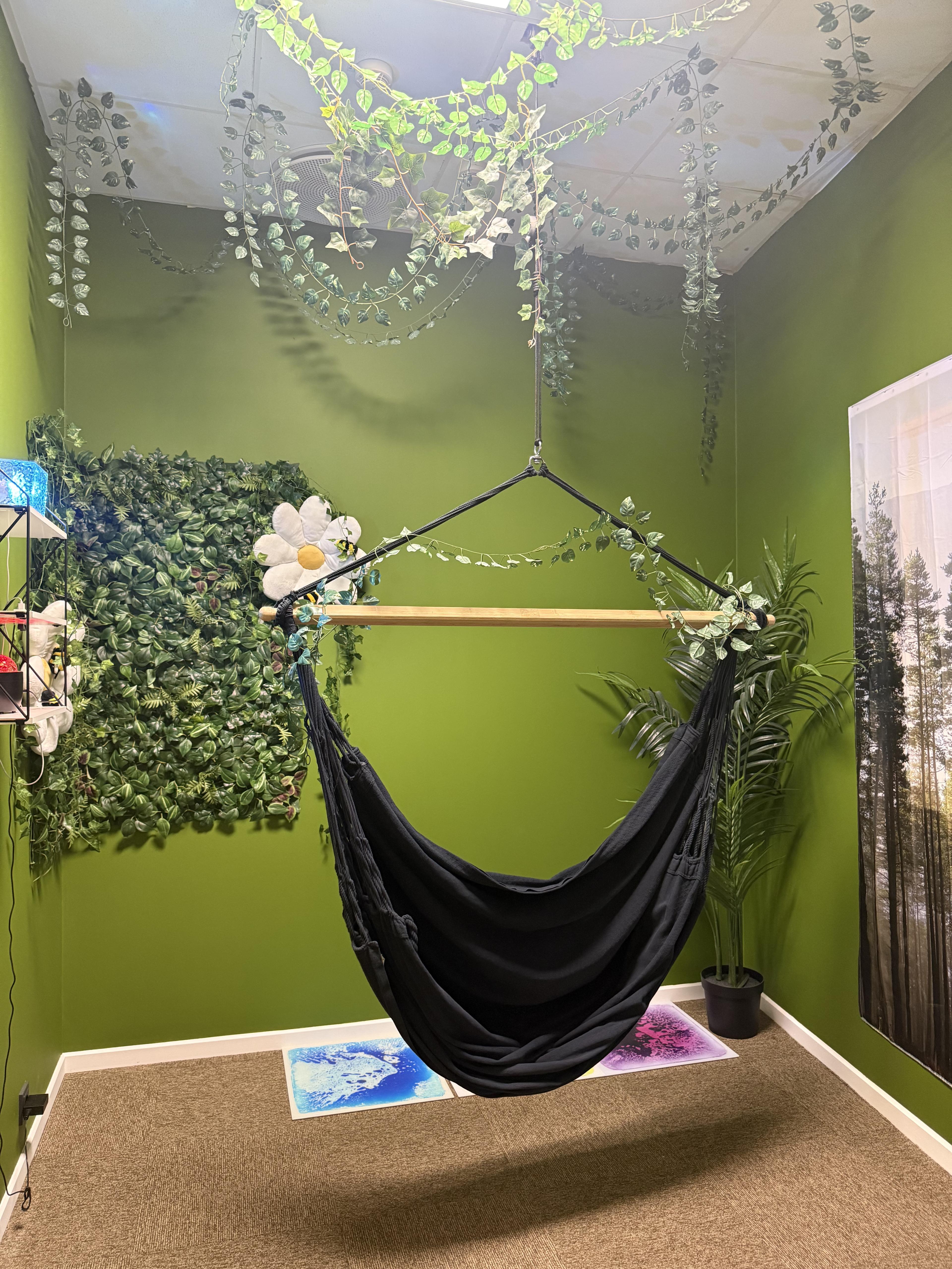 Green-painted and cozy relaxation room with a hanging chair in the center.