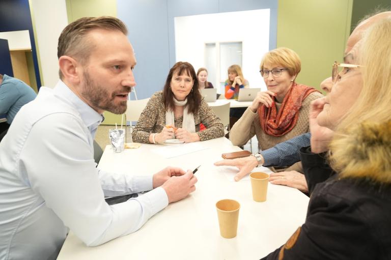 Einar Þorsteinsson situr við borð og spjallar við þrjár konur