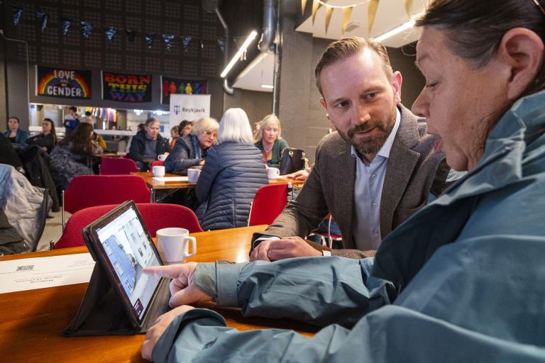 Einar Þorsteinsson borgarstjóri horfir á konu sem sýnir honum upplýsingar á spjaldtölvu á íbúafundi í Miðborg