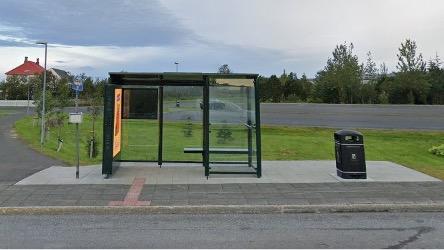 renovated bus stop with glass shelter, paving and waste container.