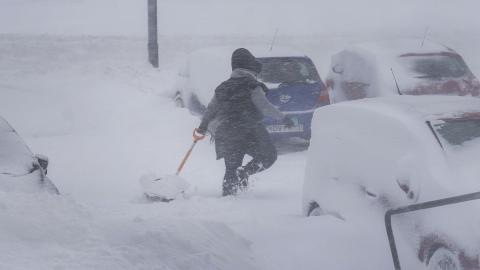 Kona að brjótast í gegnum skafl með skóflu í hendi.