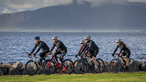 Fólk á hjóli á stíg við sjóinn. Esjan í bakgrunni.