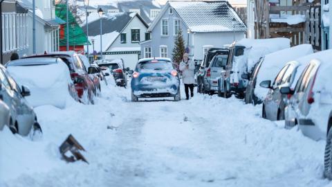 Smábíll er ekið niður götu í miðbæ Reykjavíkur í miklum snjó.