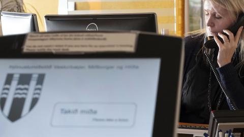 Ráðgjafi á velferðarsviði talar í síma, tölvuskjár í forgrunni. 