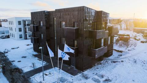 An aerial view of the housing cluster at Háteigsvegur 59, with Reykjavík City flags flying in front. 