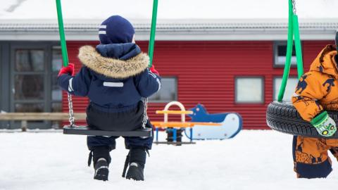 Children in swings at a preschool.