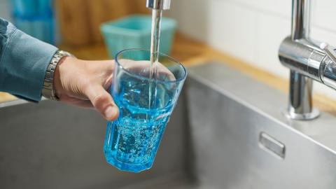 Water flowing from a tap into a glass held under the stream