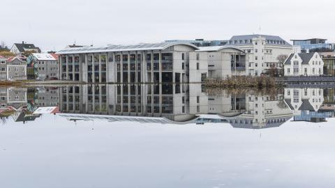 Ráðhús og húsin í kring speglast í spegilsléttri Tjörninni