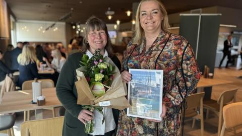 Two women with flowers and an award.