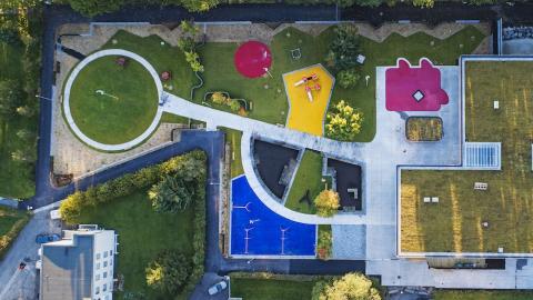 Overview image of Brákarborg preschool with grass and playground equipment.