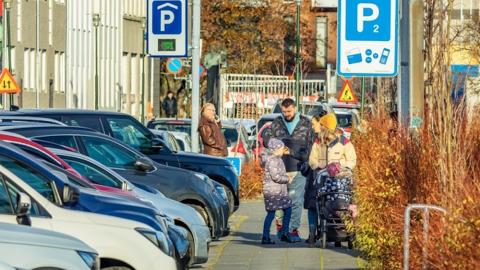 cars parked along a street with people on the sidewalk